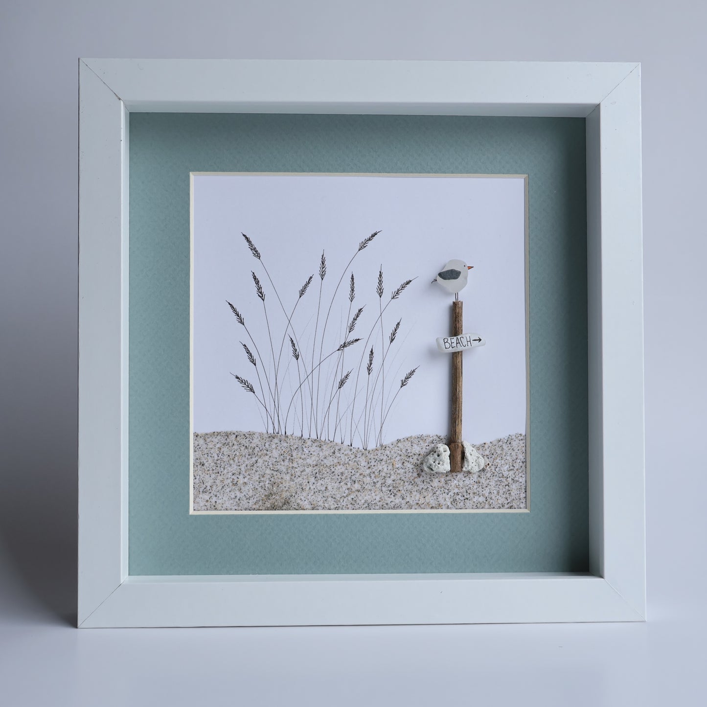 Framed artwork with a key and grasses on a light blue background