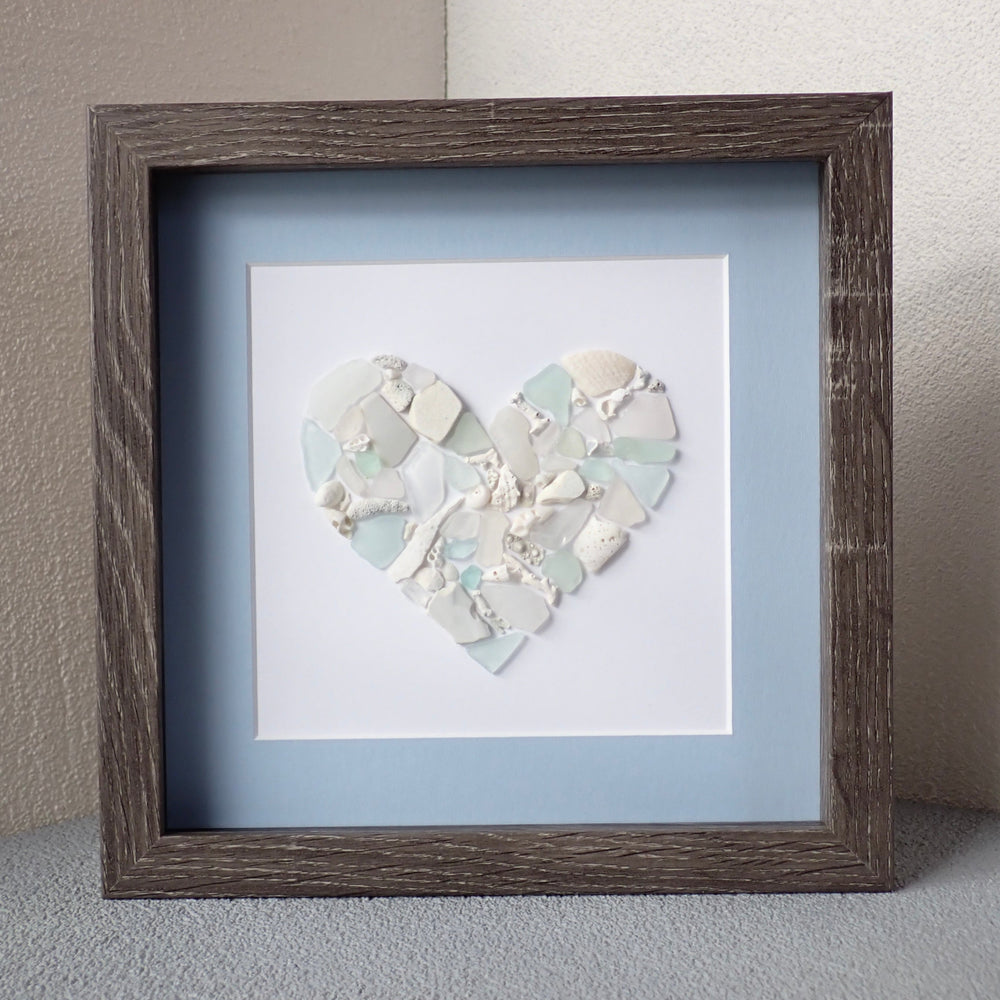 brown wood washed frame with a blue mat and a mosaic heart made from shades of blue sea glass